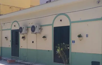 a green and white building with green doors and plants at Le casette di Elia e Alice in Palermo