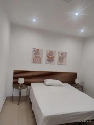 a white bedroom with a bed and a chair at Le casette di Elia e Alice in Palermo