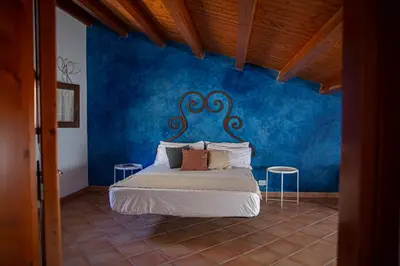a bedroom with a bed with a blue wall at Villa Luna Scopello in Castellammare del Golfo