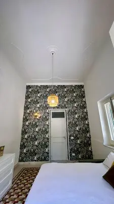 a bedroom with a white bed and a patterned wall at Don Bosco Suite in Palermo
