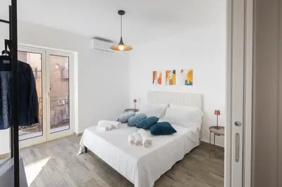 a white bedroom with a bed with blue pillows at Aromarìa Palace in Palermo