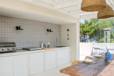a kitchen with white cabinets and a wooden table at Villa Ippolita - Studio with Esclusive Terrace in San Vito lo Capo