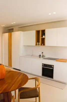 a kitchen with white cabinets and a wooden table at Villa Ippolita - Apartment with Exclusive Garden in San Vito lo Capo