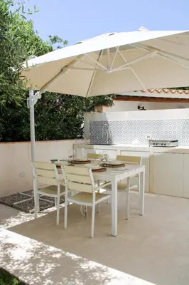 a white table and chairs under an umbrella at Villa Ippolita - Apartment with Exclusive Garden in San Vito lo Capo