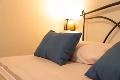 a bed with a blue pillow on top of it at Kemonia home in Palermo