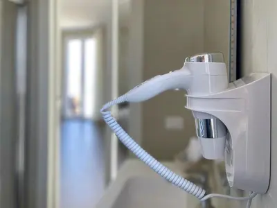 a white hair dryer hanging on a wall at Settimo Cielo al Massimo Guest House in Palermo