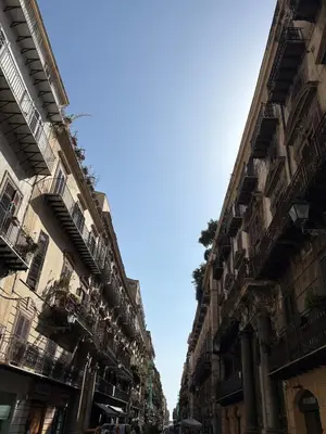 a street with buildings with balconies and a blue sky at That's Amuri in Palermo