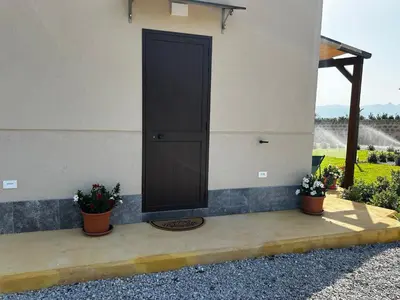 a black door on the side of a building with two plants at Case Vacanze Villa Parisi in Bagheria