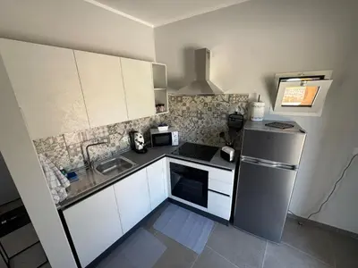 a kitchen with white cabinets and a stainless steel refrigerator at Case Vacanze Villa Parisi in Bagheria