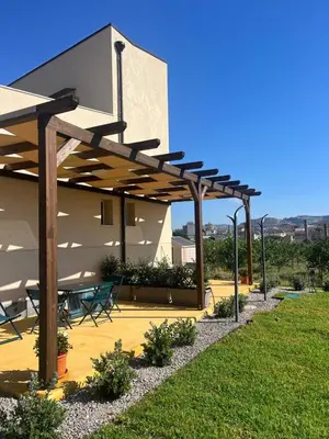a patio with a table and chairs under a wooden pergola at Case Vacanze Villa Parisi in Bagheria
