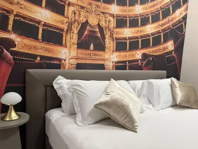 a bed with white pillows in front of a theatre at Lolli Boutique & SPA Al Massimo in Palermo