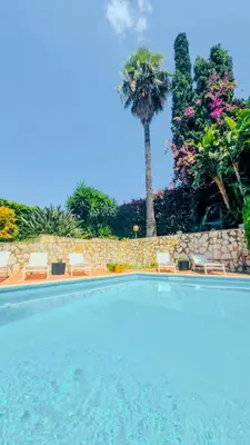 a swimming pool with chairs and a palm tree at Domus Dea in Mondello