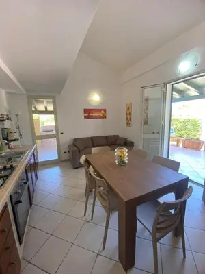 a kitchen and dining room with a wooden table and chairs at Villa Maria in Campofelice di Roccella