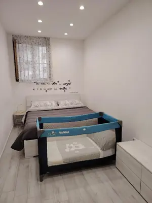 a white bedroom with a bed and a tv at La Casetta di Nonno Settimo in Palermo