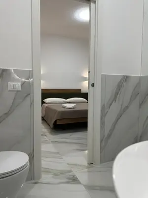 a bedroom with a bed and a toilet and a mirror at BreMi Rooms B&B in San Vito lo Capo