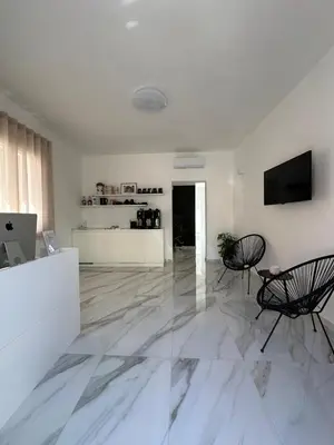 a white living room with two chairs and a television at BreMi Rooms B&B in San Vito lo Capo