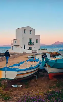 a group of boats sitting on the beach in front of a building at Casetta Bianca Luxury in Santa Flavia