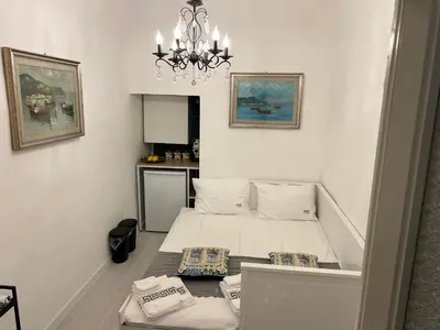 a small bedroom with a bed and a chandelier at Appartamenti Tiffany & Timi in Carini