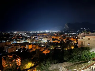 a city at night with a mountain in the background at Appartamenti Tiffany & Timi in Carini