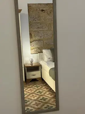 a mirror reflecting a bedroom with a bed and a nightstand at Appartamenti Tiffany & Timi in Carini