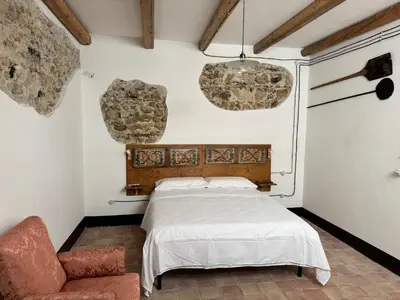 a bedroom with a bed and a chair at Antica Dimora Vaglica in Palermo