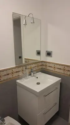 a bathroom with a white sink and a mirror at Le case di Giù in Palermo