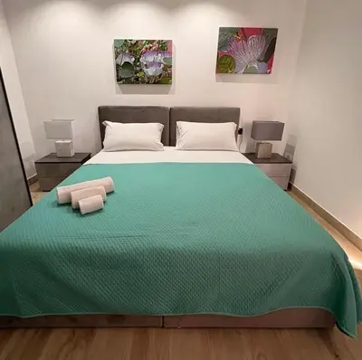 a bedroom with a large bed with a green comforter at Ottolune Accomodations in Campofelice di Roccella