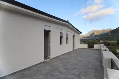 a white house with a patio with mountains in the background at Twins House Vacation Home in Carini
