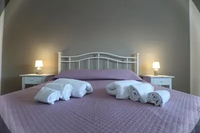 a bed with towels on it with two night stands at Twins House Vacation Home in Carini