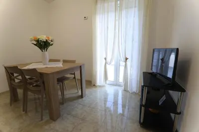 a dining room table with a television and a vase of flowers at Twins House Vacation Home in Carini
