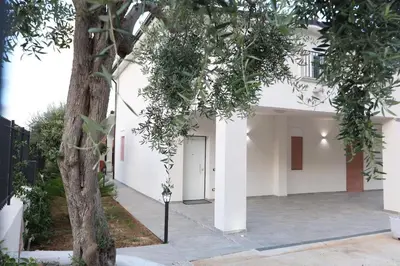 a white building with a tree in front of it at Twins House Vacation Home in Carini