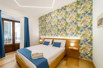 a bedroom with a king sized bed with a tropical wallpaper at Bed & Theatre - Palermo in Palermo