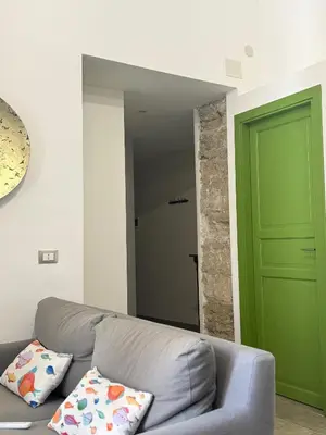 a living room with a gray couch and a green door at santa Rosalia home in Palermo