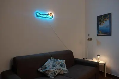 a couch with a neon sign on the wall at Romantichouse in Palermo