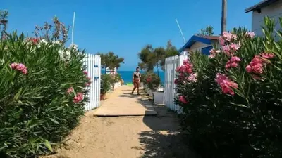 a woman walking down a path next to a white fence at lia&gio' in Campofelice di Roccella