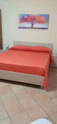 a bed in a room with a red bedspread at Sicily's Garden in Bagheria