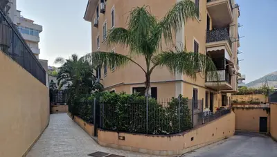 a palm tree in front of a building at Sicily's Garden in Bagheria