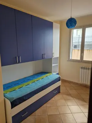 a bedroom with a bed with blue cabinets and a window at Sicily's Garden in Bagheria