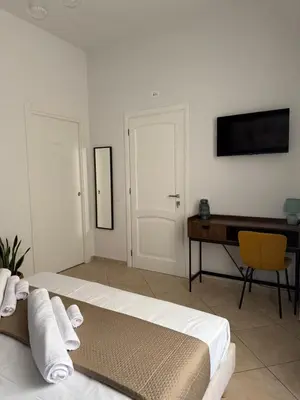 a bedroom with a bed and a desk and a television at Magione House Rooms in Palermo