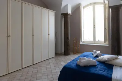 a bedroom with a bed with blue sheets and a window at Dimora Artale Suite in Palermo