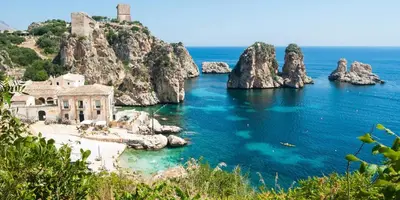 an island with rocks in the water and a building at Appartamento vista mare in Castellammare del Golfo