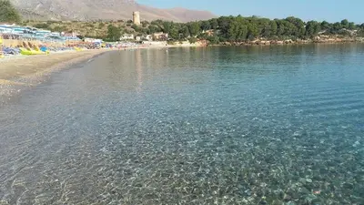 a beach with a body of water and some trees at Appartamento vista mare in Castellammare del Golfo