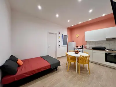 a bedroom with a bed and a table and a kitchen at GiraSole in Palermo
