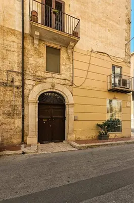 a building with a black door and a balcony at Artista Apartment in Alcamo
