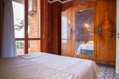 a bedroom with a bed and a wooden cabinet at Solemar Sicilia - Villa Giovitto in Bagheria