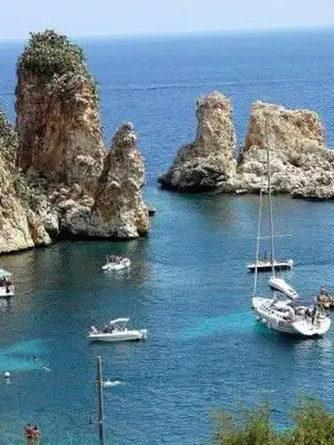 a group of boats in the water next to cliffs at La casa di Tiziana in Castellammare del Golfo