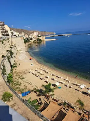 a beach with chairs and umbrellas in the water at La casa di Tiziana in Castellammare del Golfo