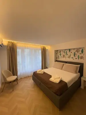 a bedroom with a bed and a chair and a window at Vivimi Deluxe Apartment in Palermo