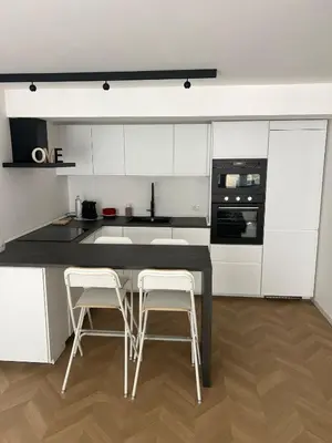 a kitchen with white cabinets and a black table and stools at Vivimi Deluxe Apartment in Palermo