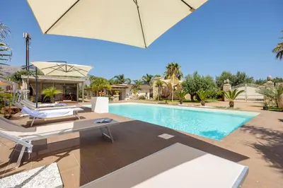 a pool with chairs and an umbrella next to a house at 14th Oasis Villa With Private Pool Near Palermo in Carini